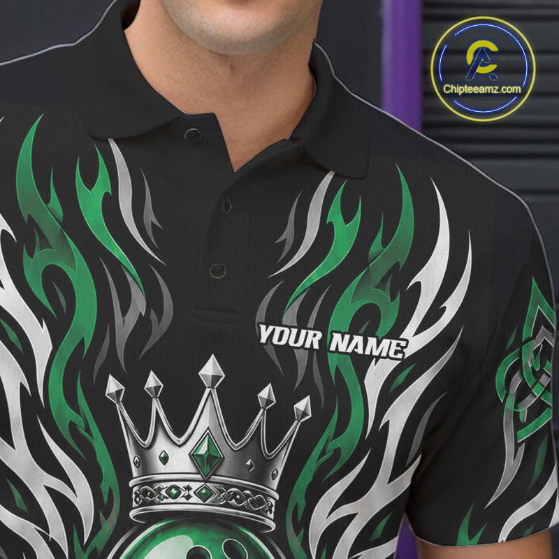 A close-up of a black short-sleeve polo shirt worn by a model, featuring a green and white flame design, a silver crown graphic, and the text 'YOUR NAME' on the chest.