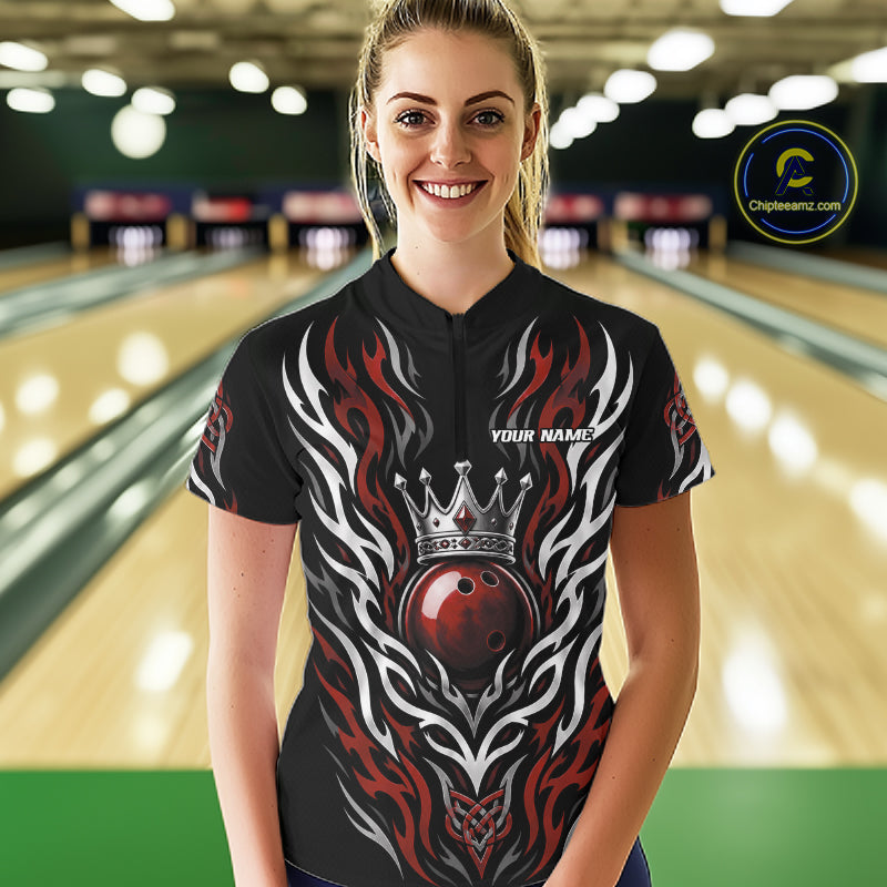 A woman wearing a custom bowling quarter zip jersey with a black base, red and white flame patterns, and a red bowling ball wearing a silver crown. 