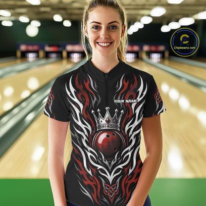 A woman wearing a custom bowling quarter zip jersey with a black base, red and white flame patterns, and a red bowling ball wearing a silver crown. 