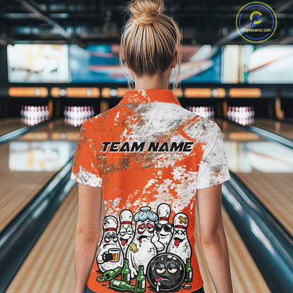Back view of a female model in a bowling lane wearing an orange and white grunge splatter bowling quarter-zip shirt featuring cartoon bowling pins and bowling ball illustration.