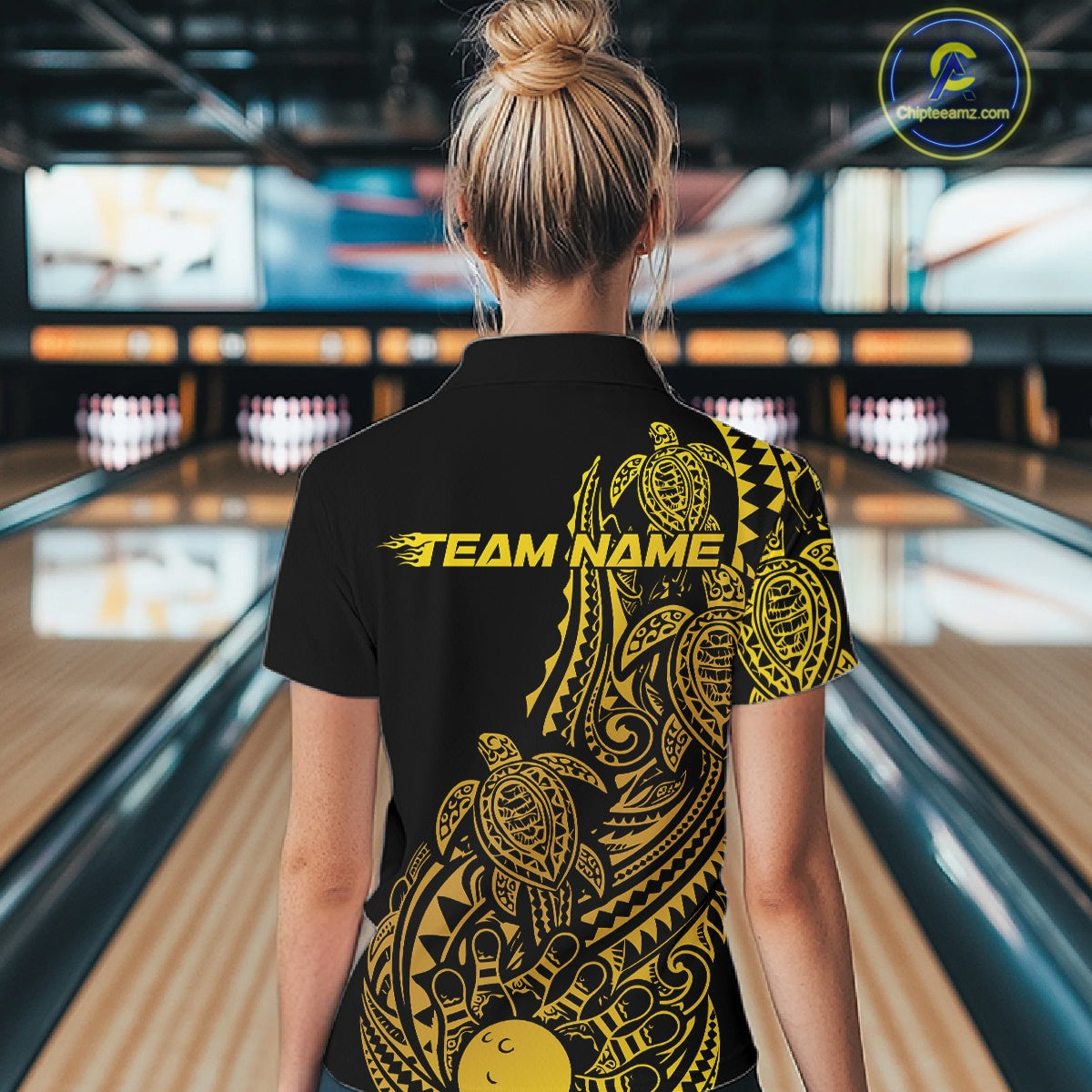 Back view of a female model in a black and gold bowling quarter-zip shirt displaying tribal bowling graphics and swirl accents.