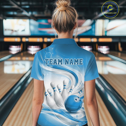 Female model standing in a bowling lane showing the back of a white and blue bowling polo shirt with abstract wave lines and a glossy bowling ball striking pins graphic.