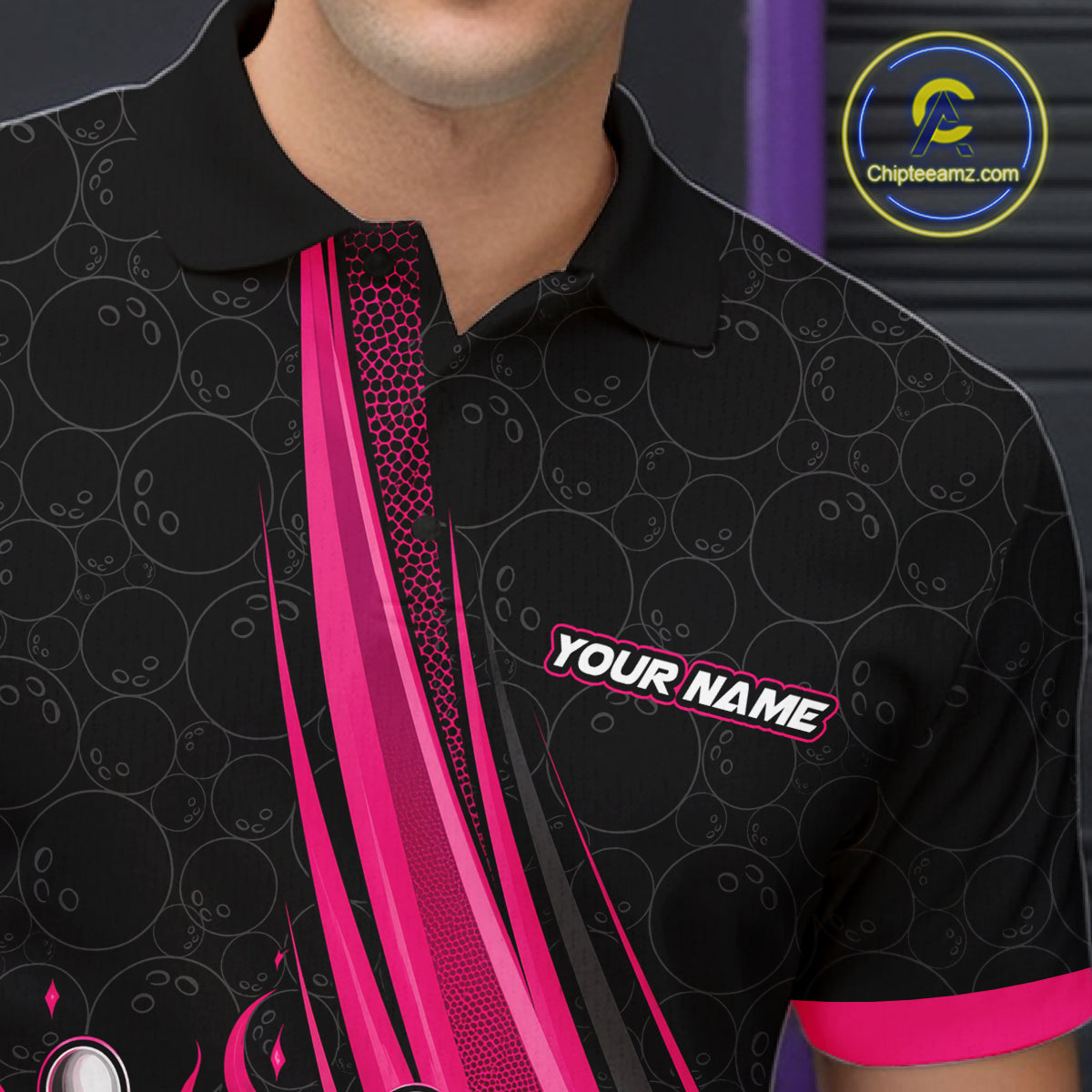 A close-up of a man wearing a black short-sleeve polo shirt with a pink and black bowling-themed graphic design, featuring a 'YOUR NAME' placeholder on the chest. 