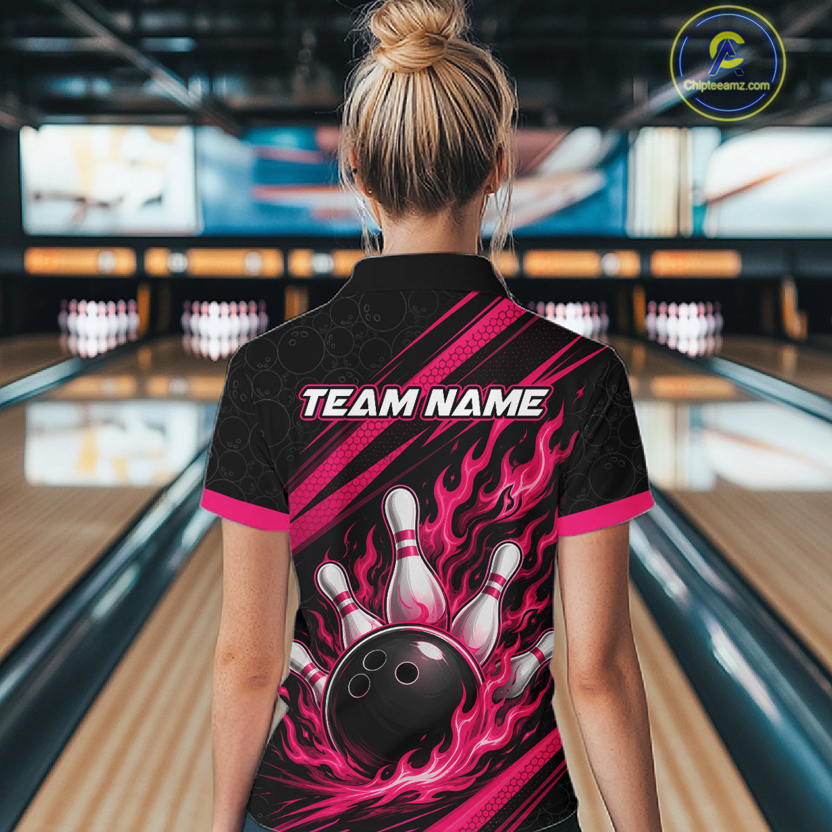 A woman viewed from behind wearing a black short-sleeve bowling-themed shirt with bright pink flame graphics, a bowling ball and pins design on the back, and 'TEAM NAME' printed across the upper back. 