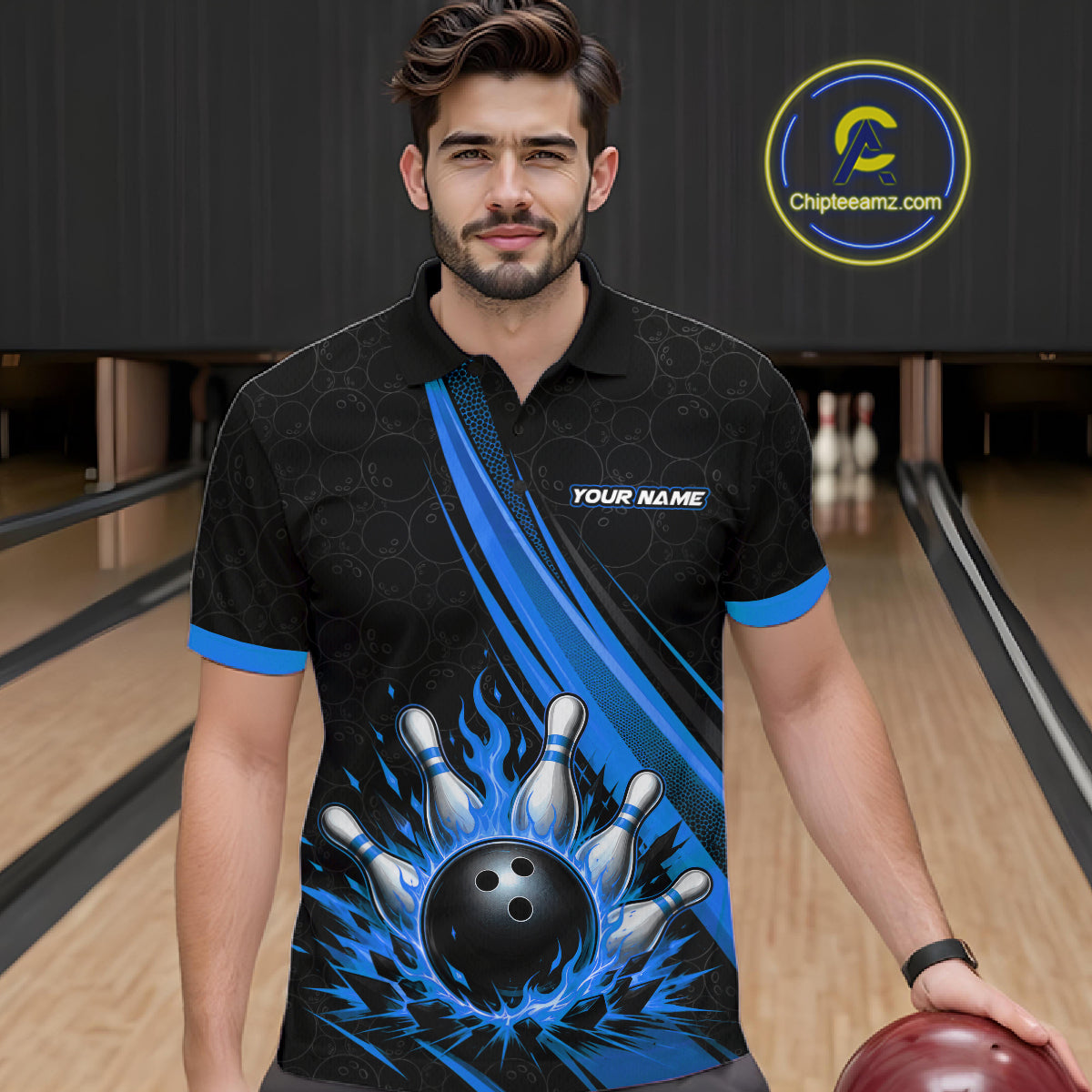 A man wearing a custom black and blue bowling-themed short-sleeve polo shirt with a graphic of bowling pins and a bowling ball, standing in a bowling alley.
