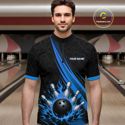 A man wearing a black and blue bowling-themed short-sleeve quarter-zip shirt with a flame bowling ball graphic, standing in a bowling alley. 