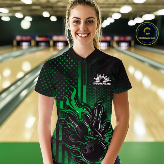 Female model wearing a black and green bowling quarter-zip shirt at a bowling lane with fiery bowling strike artwork and patriotic accents.