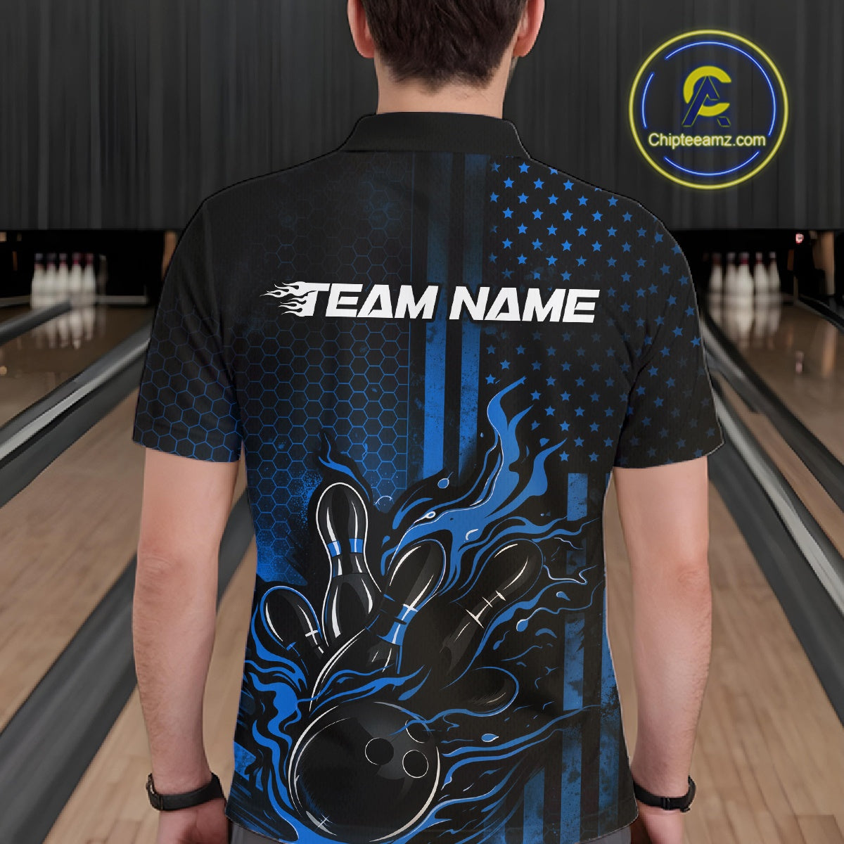 Back view of a male model in a bowling alley wearing a black and blue bowling polo featuring flames and bowling pins crashing design.