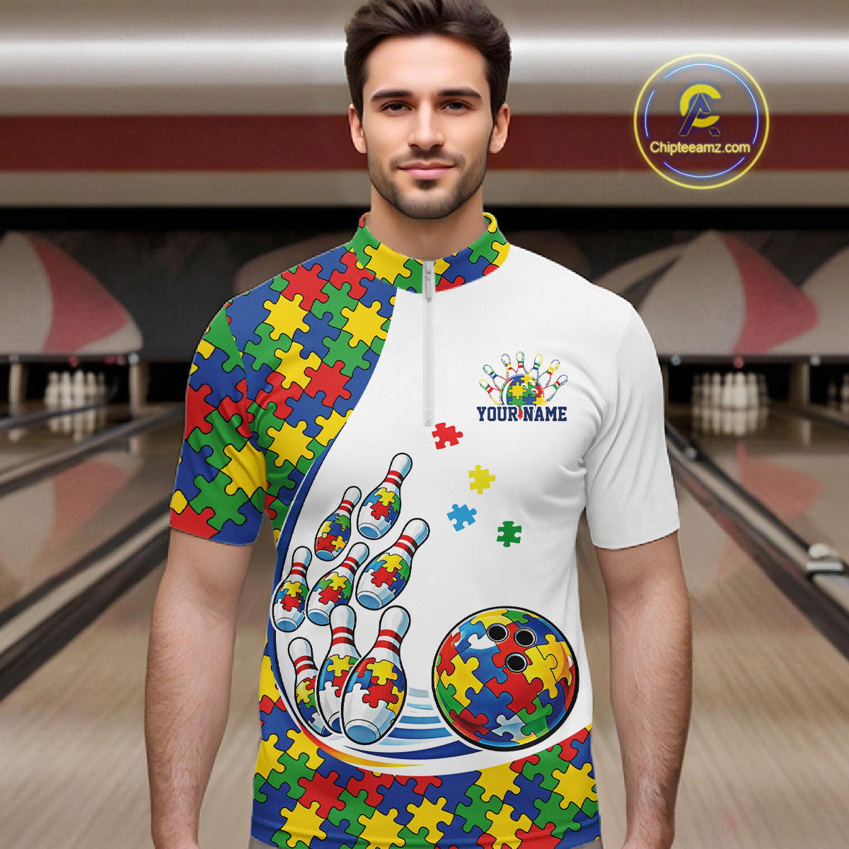 In A Bowling Lane, Front View Male Model Wearing White Quarter-Zip Shirt With Colorful Autism Bowling Strike Illustration And Puzzle Motif Graphics