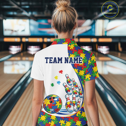 Back view of a female bowler wearing a white quarter-zip shirt, colorful autism puzzle-themed bowling design with dynamic strike elements.