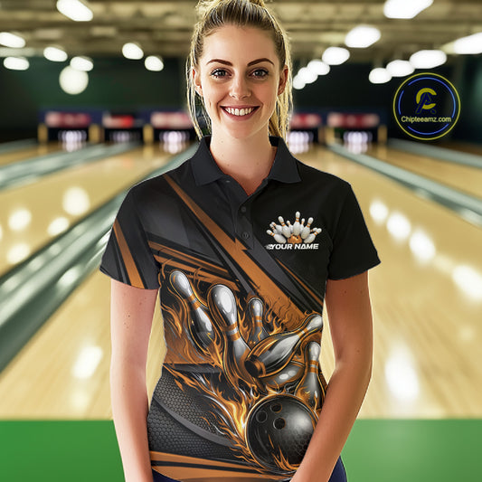 Female model in a bowling lane wearing black polo shirt, front view showcasing gold flame bowling ball hitting pins dynamic artwork