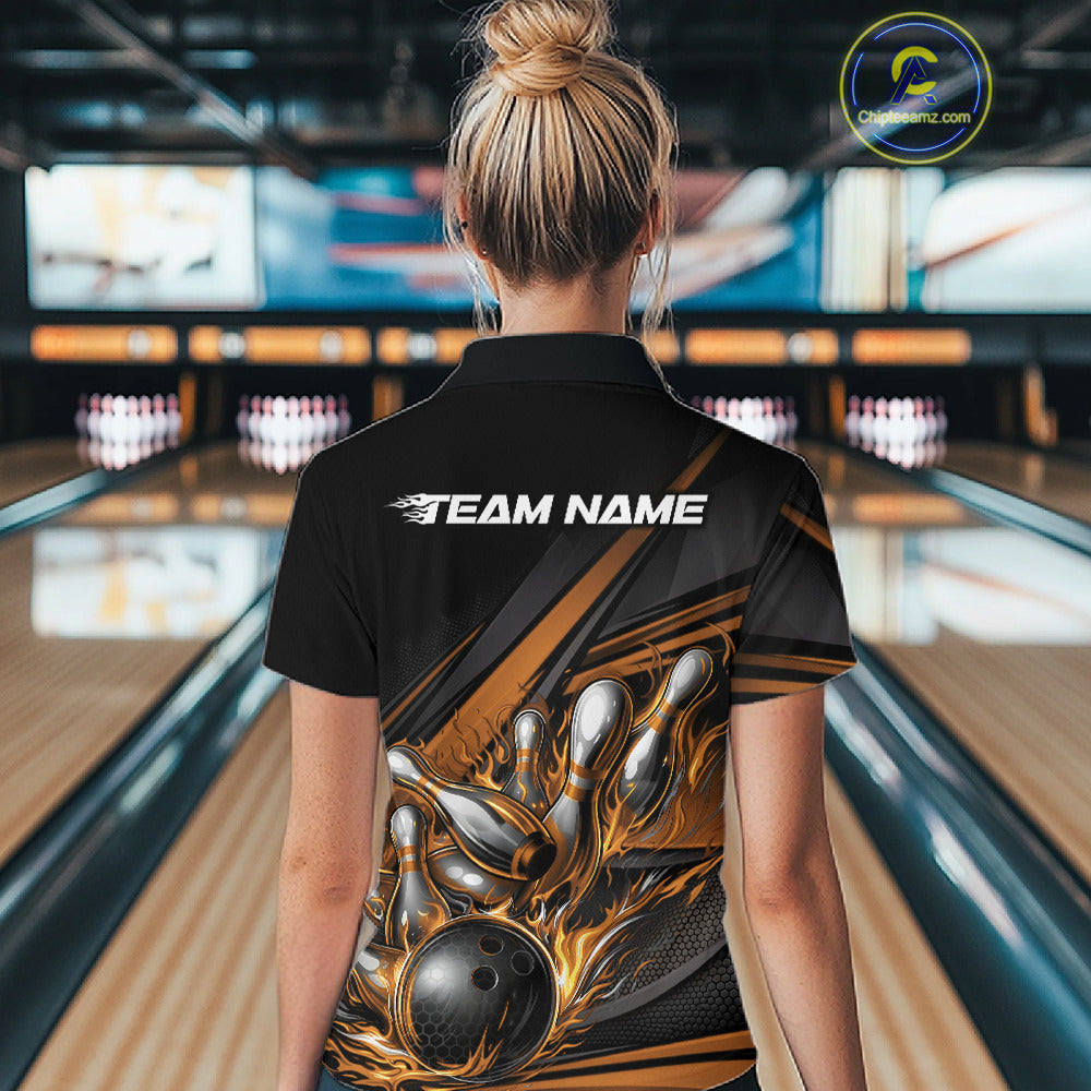 Female model in a bowling lane wearing a black polo shirt, back view featuring gold flame bowling ball striking pins with abstract geometric stripe design