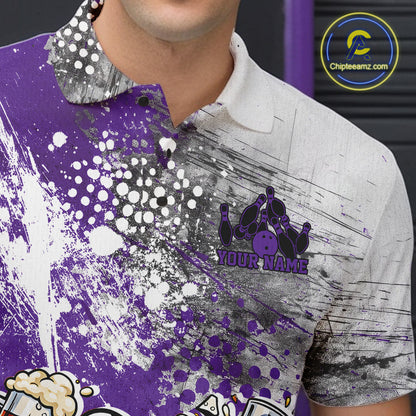 Close-up view of the left chest of a purple and white grunge splatter polo shirt showing humorous bowling ball and pin fist-fighting illustration detail.
