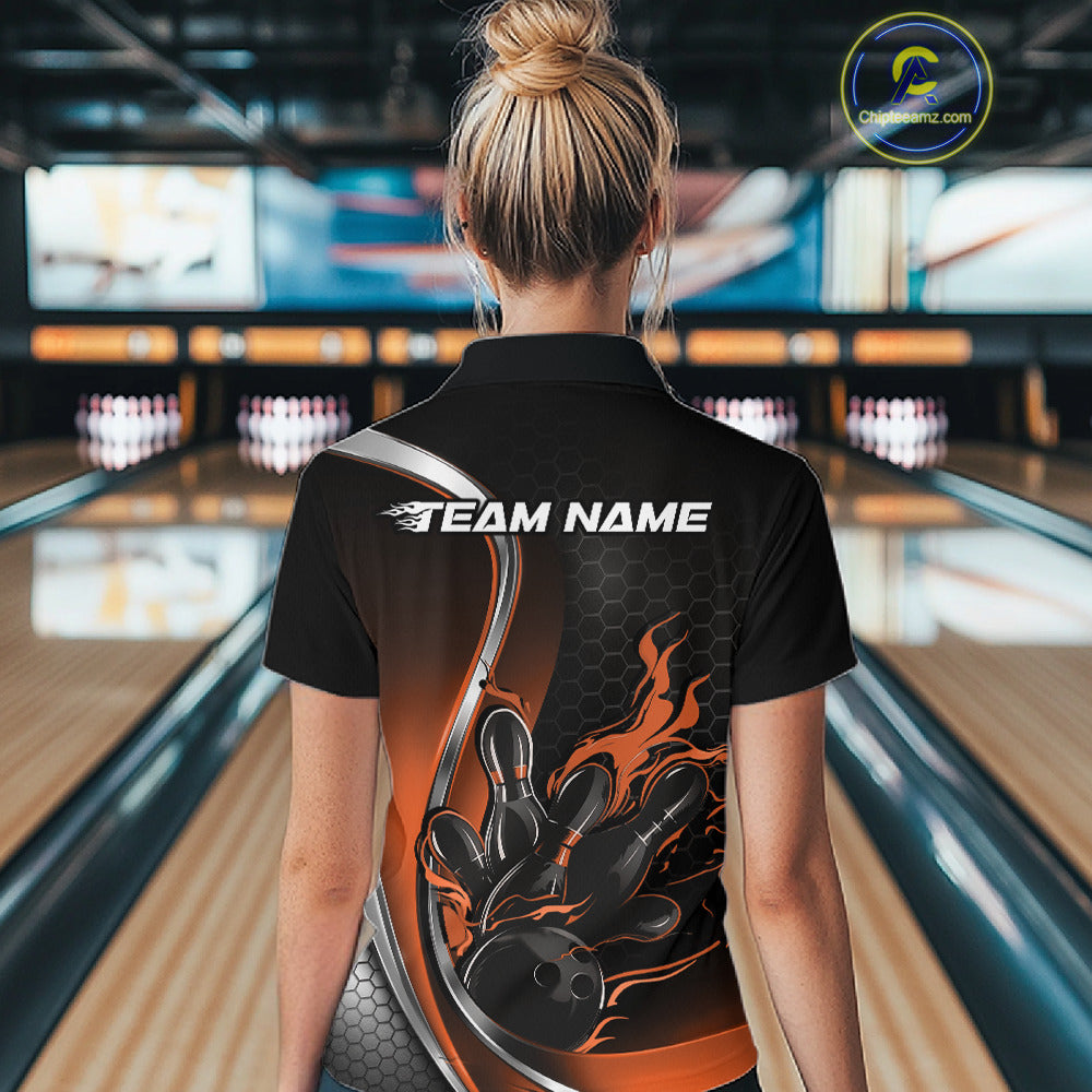 Female model back view at bowling lane wearing black and orange quarter zip shirt featuring flaming bowling ball striking pins artwork