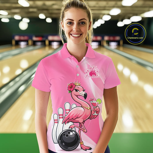 Female model wearing a pink bowling polo shirt at a bowling lane with a crowned flamingo, cocktail, bowling ball, and hibiscus flower artwork.