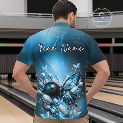 Front view of a male model in a bowling venue wearing a blue quarter-zip shirt featuring a butterfly beside a bowling ball and pins.
