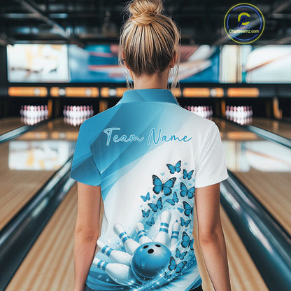 Back view of a female model wearing a white and blue bowling polo with butterfly artwork and bowling graphics at the bowling lane