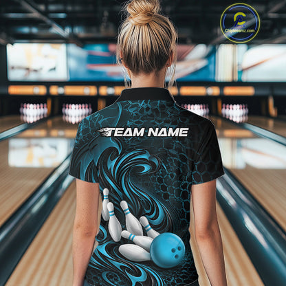 Back view of a female model wearing a black and blue bowling quarter-zip shirt in a bowling alley featuring a tribal flame bowling ball and pins graphic