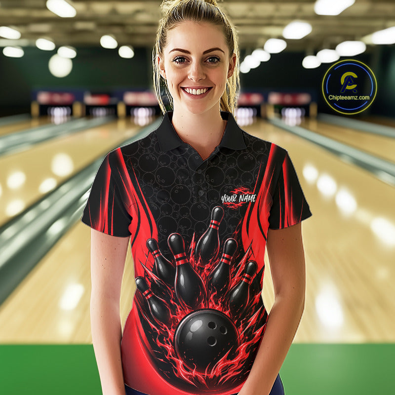 A woman wearing a black and red bowling-themed short-sleeve polo shirt stands in front of a blurred bowling alley background. The shirt features a graphic of black bowling pins and a bowling ball with red flames