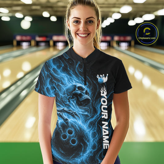 Female model wearing a black bowling quarter-zip shirt in a bowling alley featuring a skull clutching a bowling ball surrounded by swirling blue energy flames