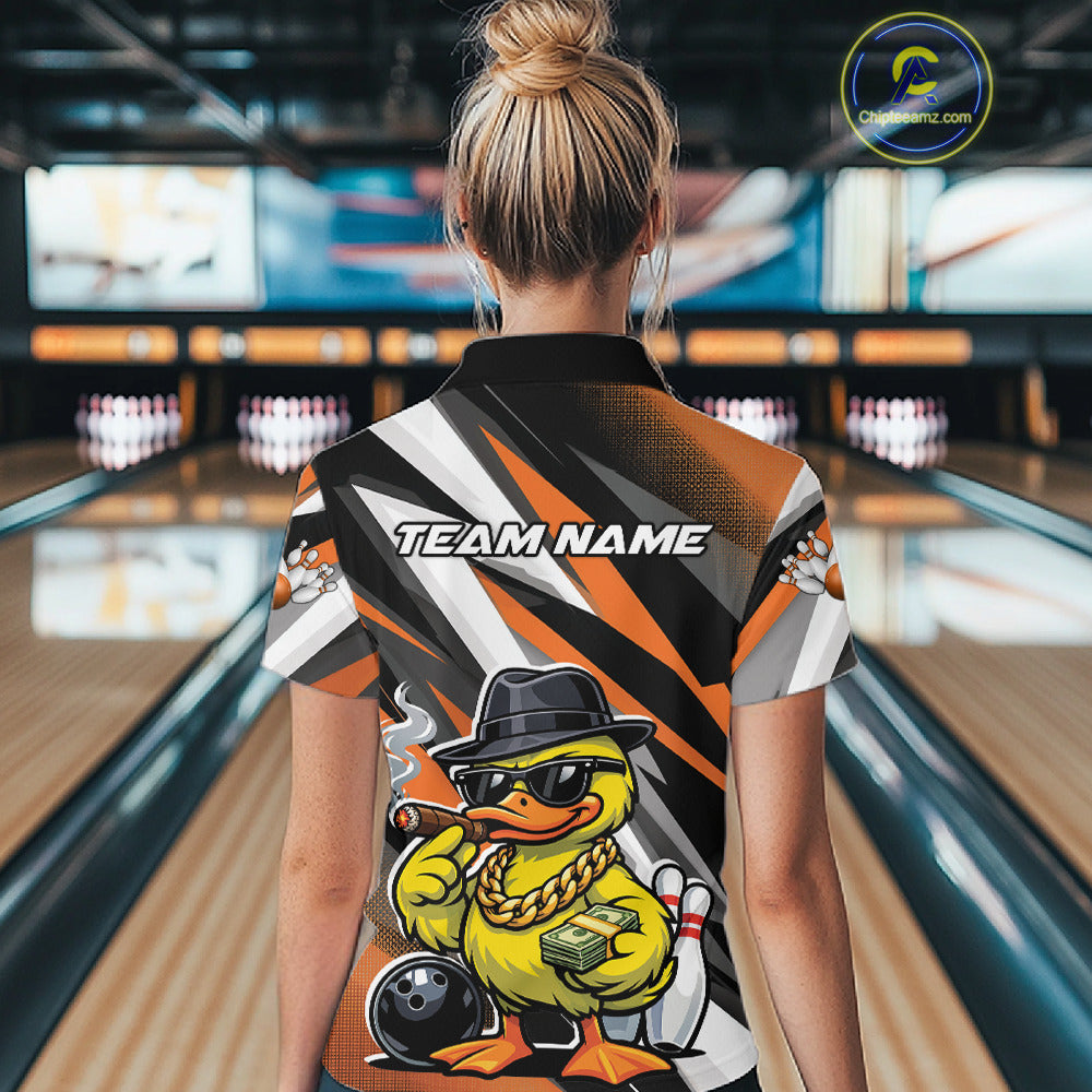 Back view female model in bowling lane wearing black and orange quarter zip featuring duck with sunglasses and fedora holding cash and cigar beside bowling ball and pins artwork.