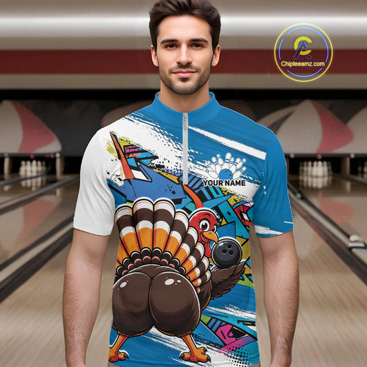 Front view of a male model wearing a blue custom quarter zip bowling shirt with a funny graffiti turkey holding a bowling ball, paint splatter accents in a bowling alley.
