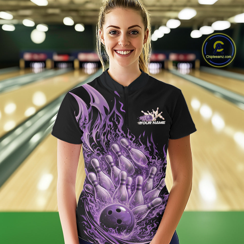 Female model in a bowling lane wearing a black and purple quarter zip shirt featuring a flaming bowling ball crashing into bowling pins with fiery design.