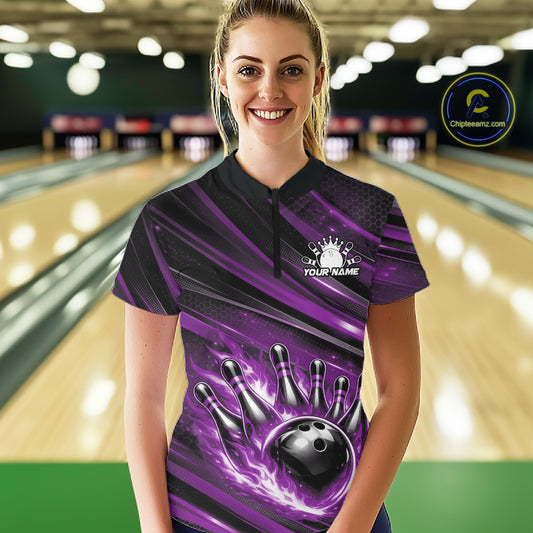 Female model in a bowling lane wearing a black and purple quarter zip shirt, front view featuring fiery bowling ball striking pins with abstract stripe design