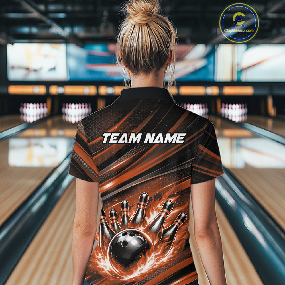 Female model at a bowling lane, back view of black and orange quarter zip shirt showcasing fiery bowling ball striking pins with abstract stripe pattern