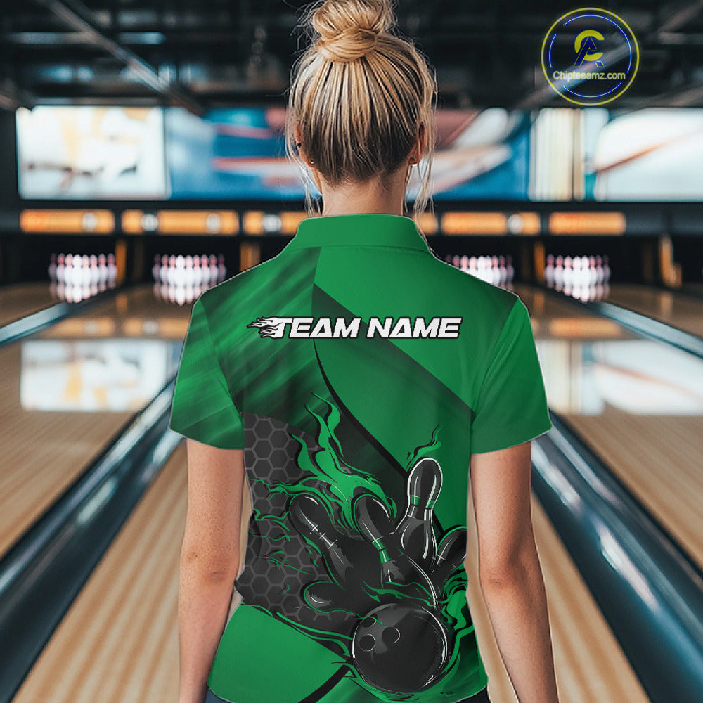 Back view of a female model in a bowling venue wearing a black and green polo shirt featuring a flaming bowling ball and pin motif.