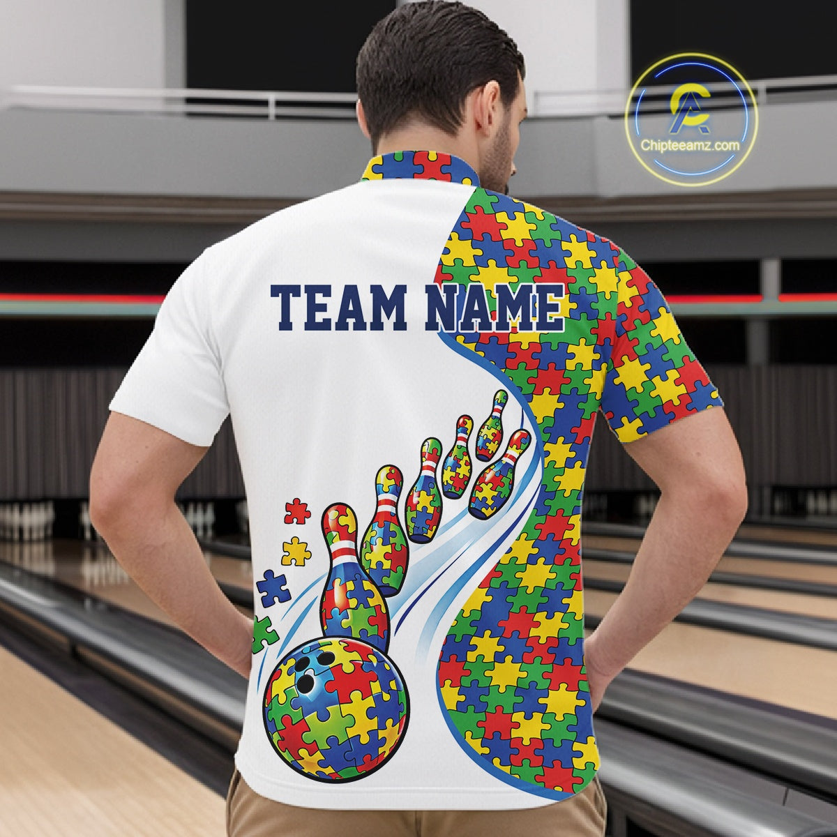Inside Bowling Center, Front View Male Model In White Quarter-Zip Shirt With Autism-Themed Bowling Strike Artwork And Multicolor Puzzle Visuals