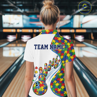 Back view of a female bowler wearing a white quarter-zip shirt, colorful autism puzzle bowling artwork with dynamic strike composition.