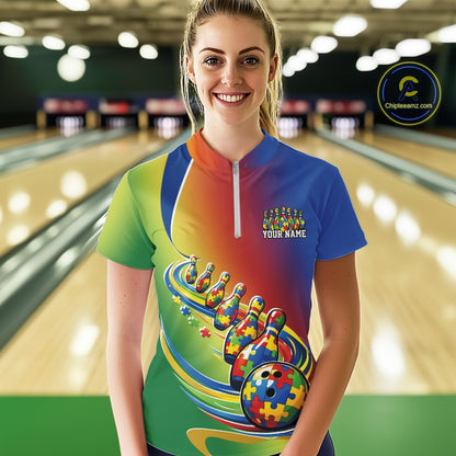Female model in a bowling lane wearing a colorful quarter-zip shirt, autism puzzle bowling ball with matching trailing bowling pins in vibrant design.