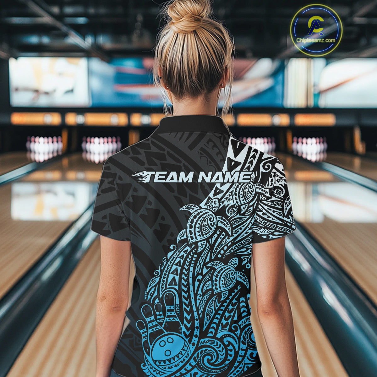Back view of a female model in a black and blue bowling polo shirt featuring tribal bowling artwork and turtle accents.