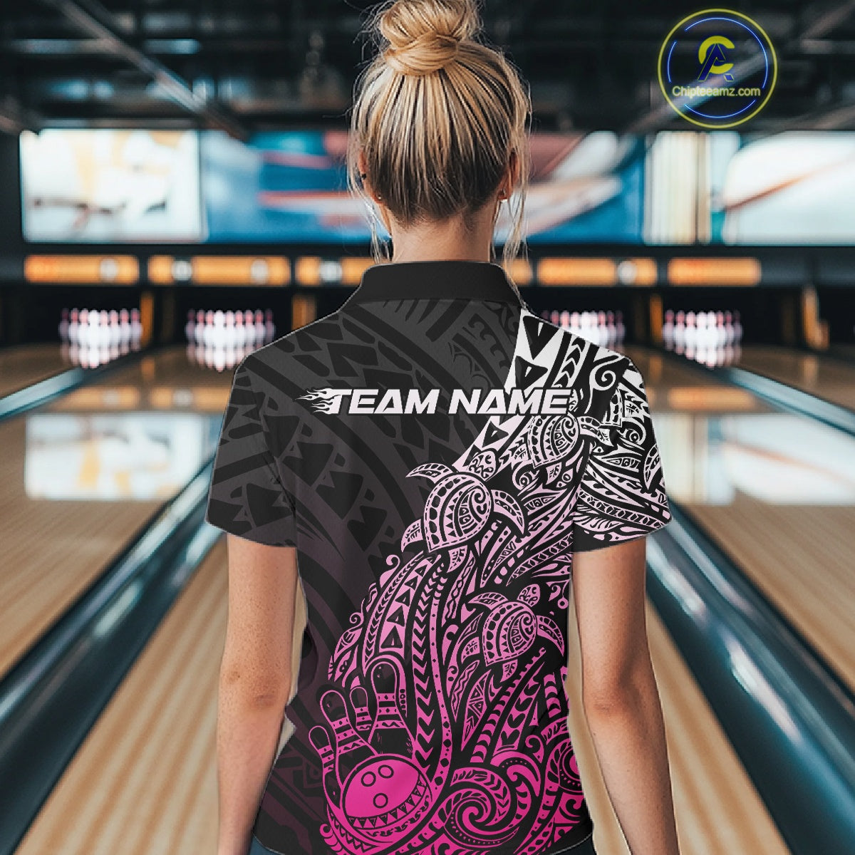 Back view of a female model in a black and pink bowling polo shirt displaying turtle Polynesian bowling graphics.