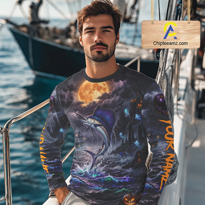 A man wearing a long-sleeve crewneck shirt with an all-over Halloween-themed graphic print featuring a marlin, full moon, and haunted house, photographed on a boat deck with a visible Chipleeamz.com watermark overlay.