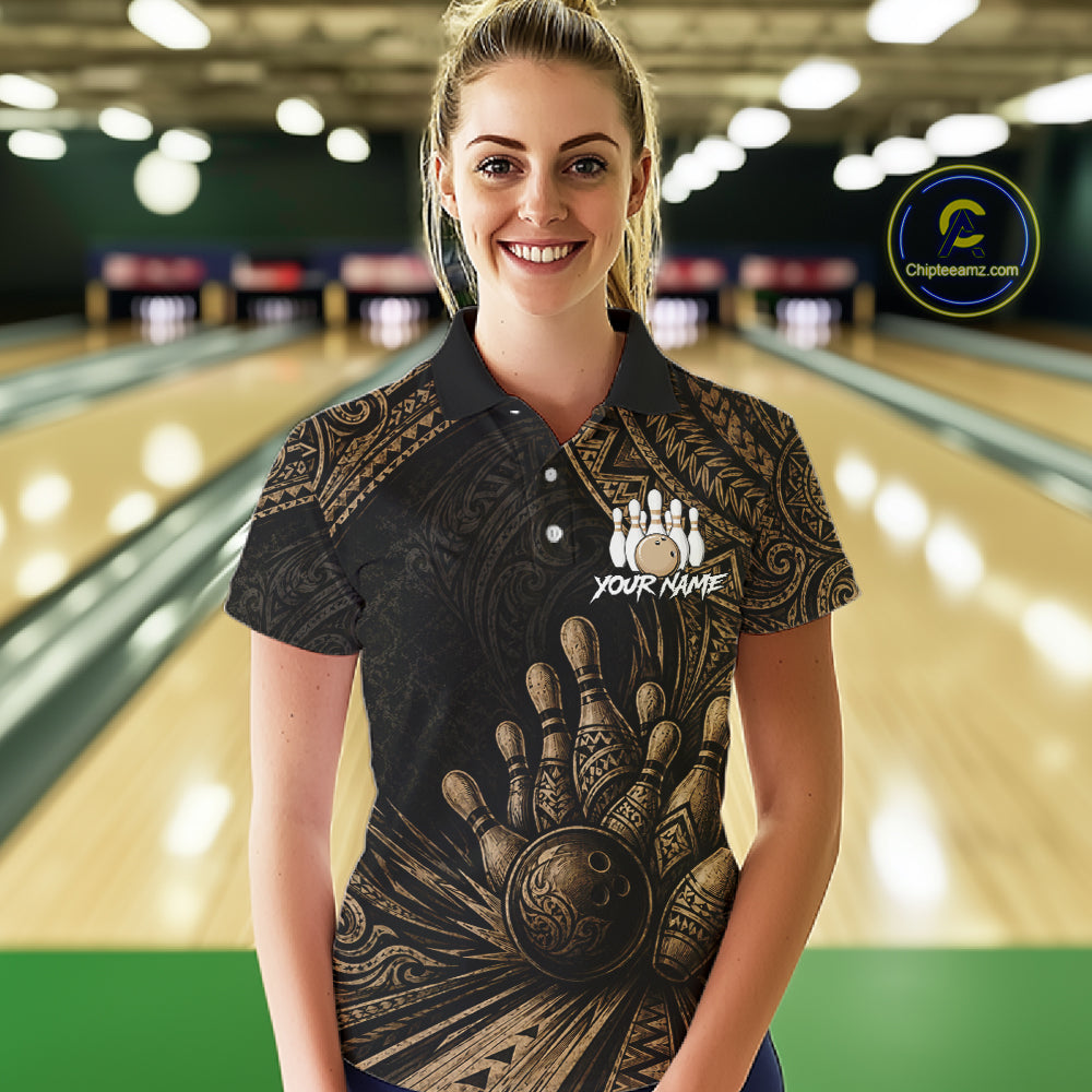 A woman wearing a black short-sleeve polo shirt with a gold bowling-themed graphic print stands in front of a blurred bowling alley background. The shirt features a large bowling hand and ball design, a bowling pins graphic, and the text 'YOUR NAME'.