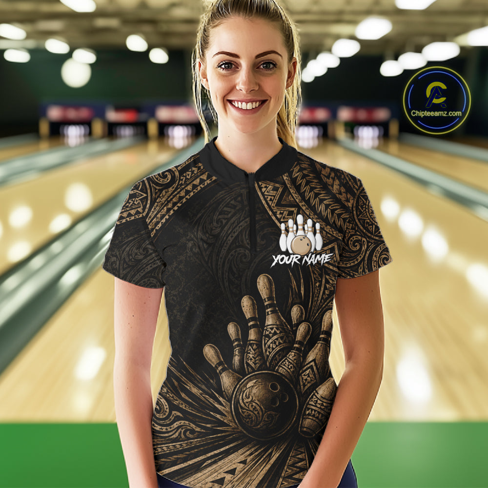 A woman standing in a bowling alley wearing a black short-sleeve bowling shirt with a brown tribal hand graphic and a white 'YOUR NAME' logo on the chest. The background shows blurred bowling lanes, and a circular 'Championship.