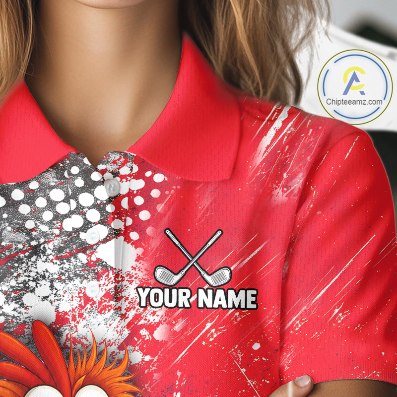 A close-up of a person wearing a red custom golf polo shirt with a graphic design featuring crossed golf clubs, paint splatters, and the text 'YOUR NAME'.