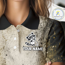 Load image into Gallery viewer, Close-up of a polo shirt with a raccoon logo and 'Your Name' text on a textured background.