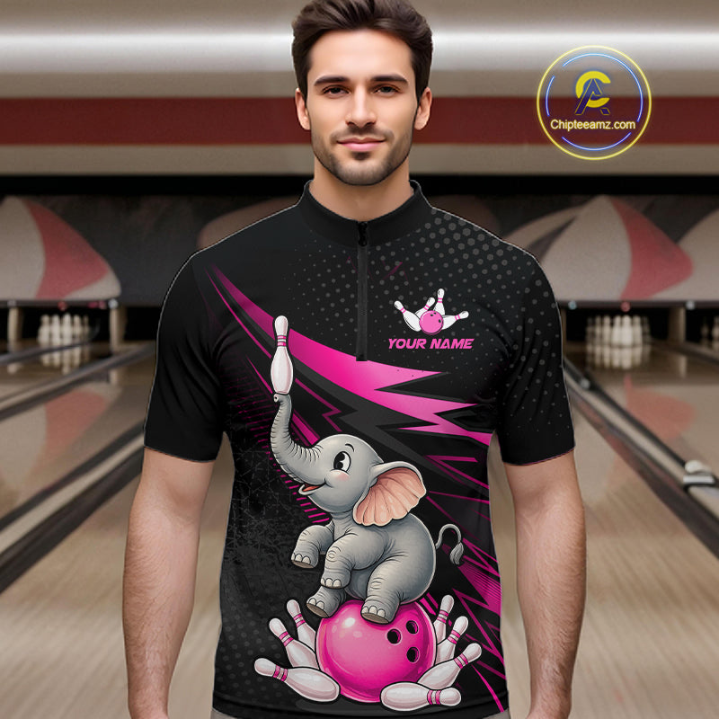 A man wearing a black short-sleeve quarter-zip bowling-themed t-shirt with a cartoon elephant, pink bowling ball, and bowling pins on the front. The background shows blurred bowling alley lanes.