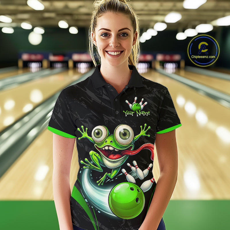 A woman stands in a bowling alley wearing a black short-sleeve polo shirt with a large green cartoon frog graphic and bright green trim. The shirt has a mock logo reading 'Your Name' and a visible 'Chipteeamz"