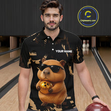 Load image into Gallery viewer, Man wearing a black shirt with a capybara holding a bowling ball design in a bowling alley.