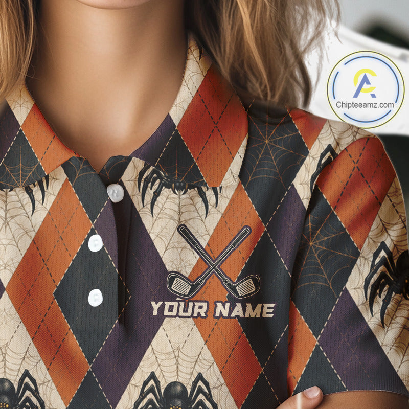 A close-up of a person wearing a collared polo shirt with a Halloween-themed argyle pattern in orange, black, and beige, featuring spiderwebs, spiders, and crossed golf clubs with the text 'YOUR NAME'.