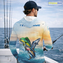 Load image into Gallery viewer, Angler wearing mahi mahi wahoo tuna blue hooded performance fishing shirt on boat with custom team name on the back