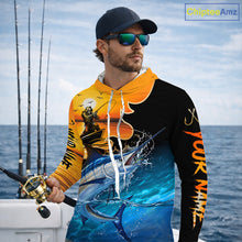 Load image into Gallery viewer, Man wearing a colorful long sleeve hooded fishing shirt with a design of a marlin fish and a fish reaper, standing on a boat with fishing rods in the background.