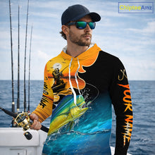 Load image into Gallery viewer, Man wearing a colorful long sleeve hooded fishing shirt with a design of a mahi mahi fish and a fish reaper, standing on a boat with fishing rods in the background.