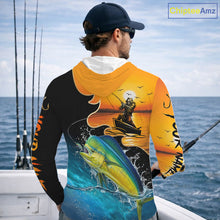 Load image into Gallery viewer, Person wearing a saltwater long sleeve hooded fishing shirt with a sunset and fish reaper design, standing on a boat.