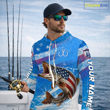 Load image into Gallery viewer, Man wearing a patriotic northern pike fishing shirt with custom name, holding a fishing rod on a boat.