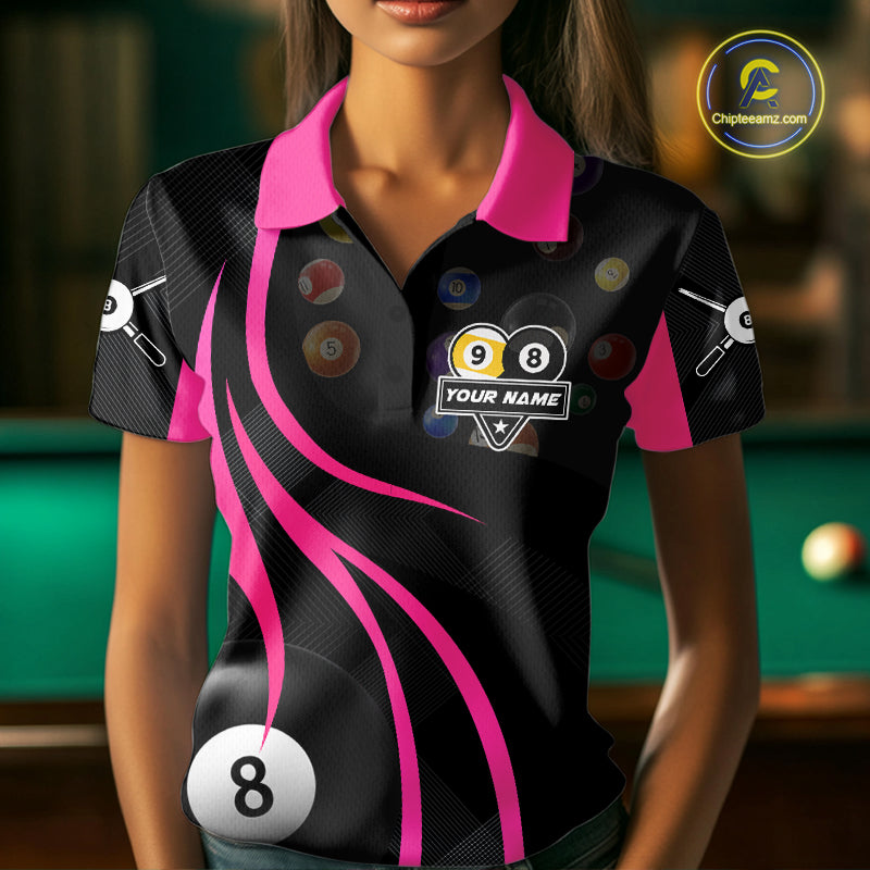 Woman wearing a pink 8 ball and 9 ball billiard jersey beside a pool table front view.